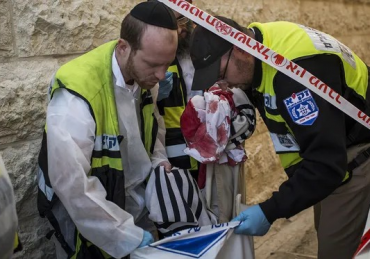 Emergency personnel holding a bloody prayer shawl