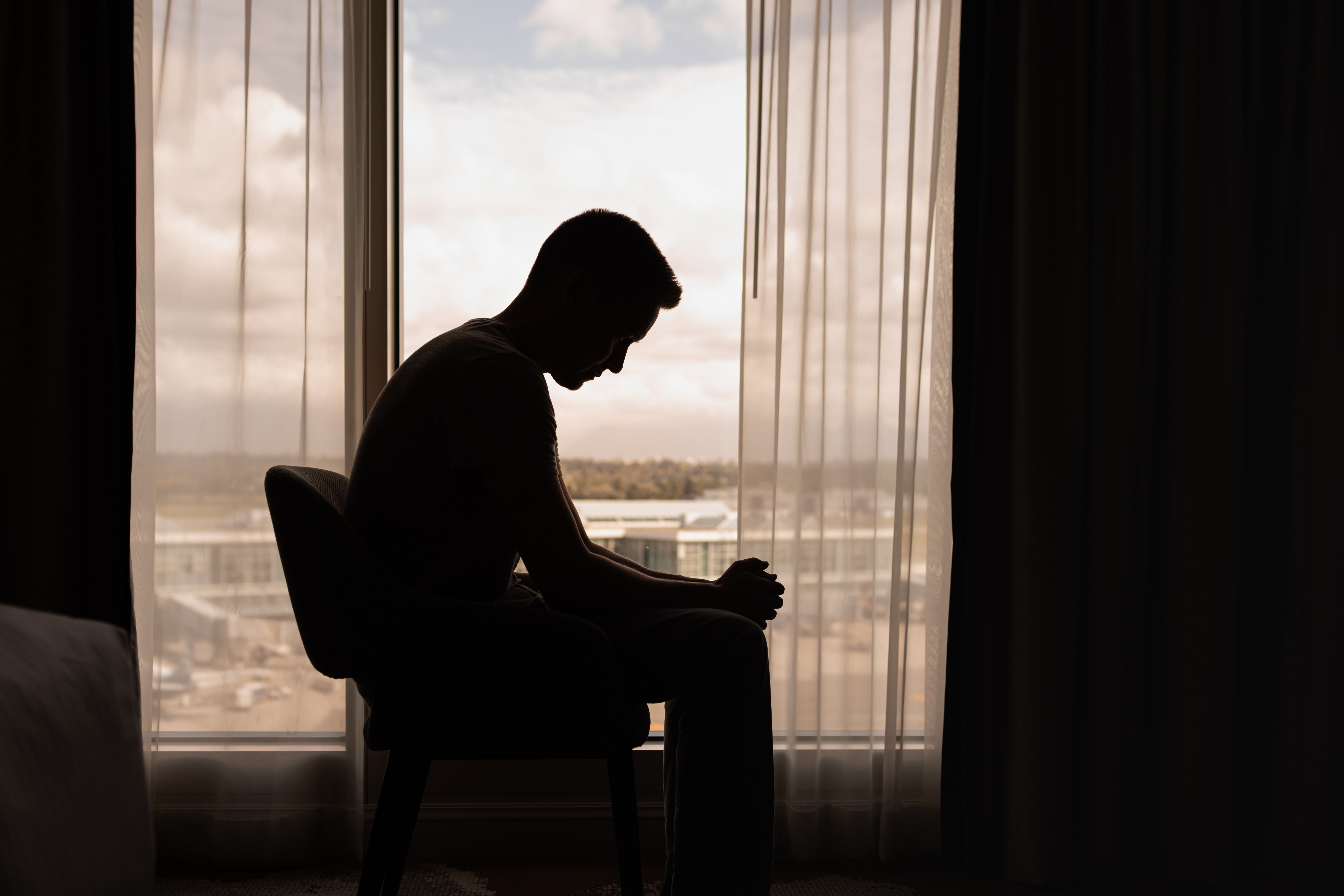 depressed man sitting by a window